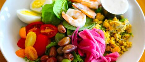 A salad with various ingredients including lettuce, tomatoes, olives, and shrimp.