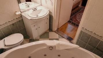Een badkamer met een groot bad, een wastafel en een toilet.