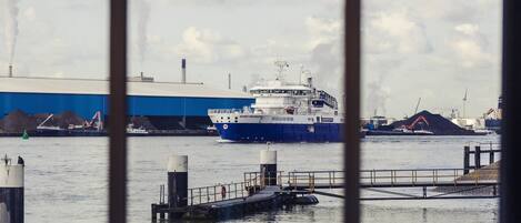 A large industrial ship docked at a port with a blue building in the background.