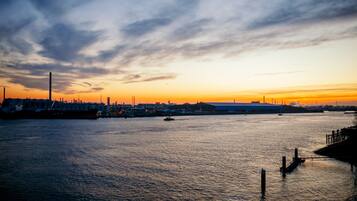 A sunset over a calm river with industrial buildings in the background.