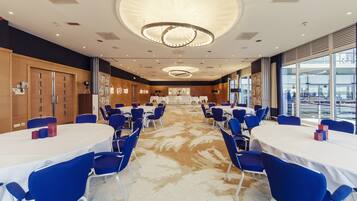 A conference room with round tables, blue chairs, and a large window offering a view of the outside.
