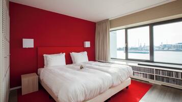 Ein modernes Hotelzimmer mit einem großen Bett, roten Wänden und Blick auf die Stadt.