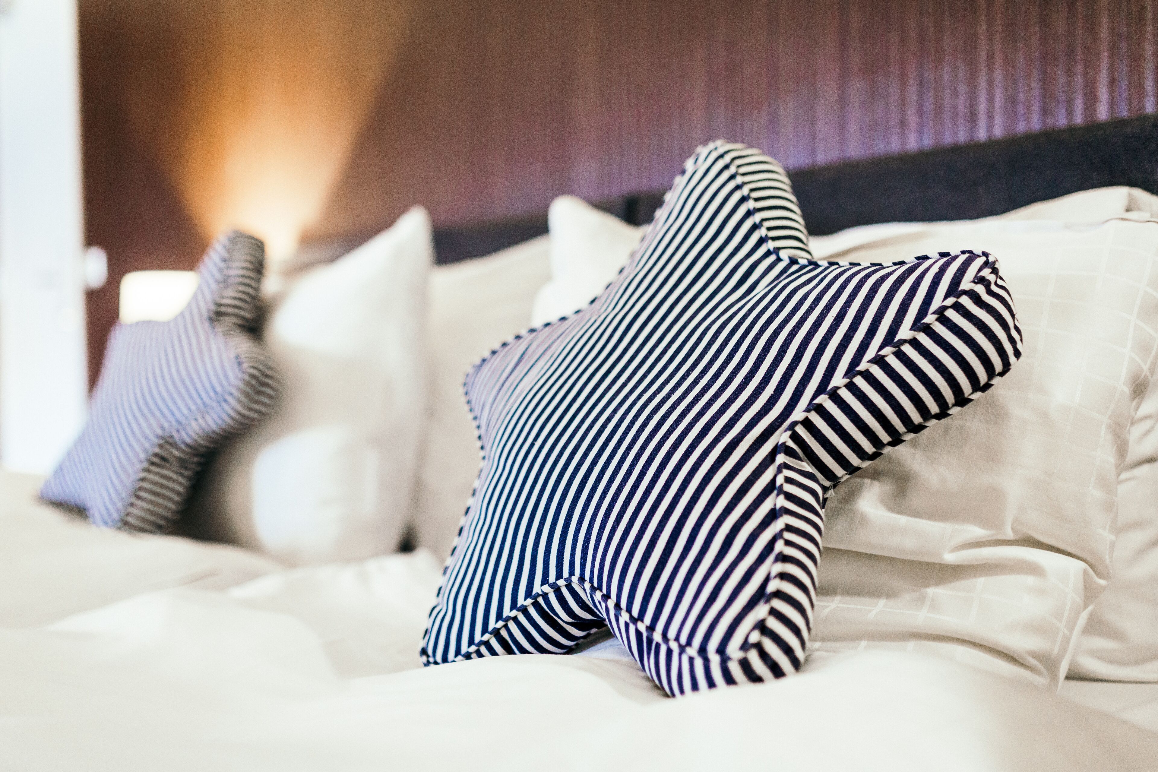 Een bed met gestreepte kussens en een witte deken.