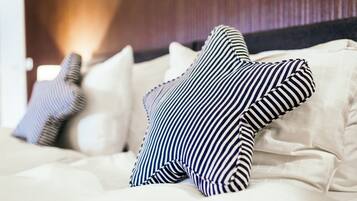 Een bed met gestreepte kussens en een witte deken.