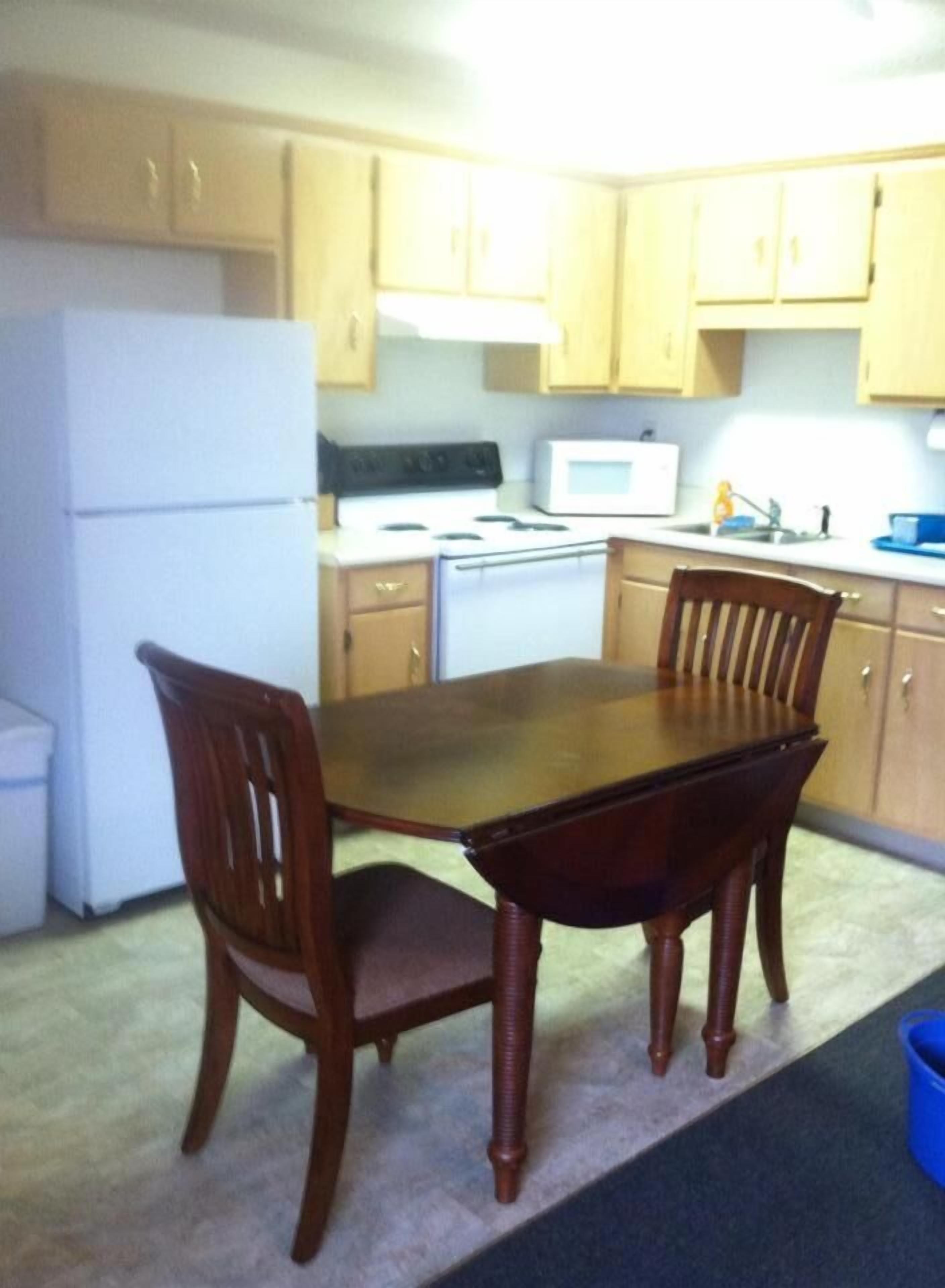 A compact kitchen with wooden cabinets, a white refrigerator, a stove, and a microwave.