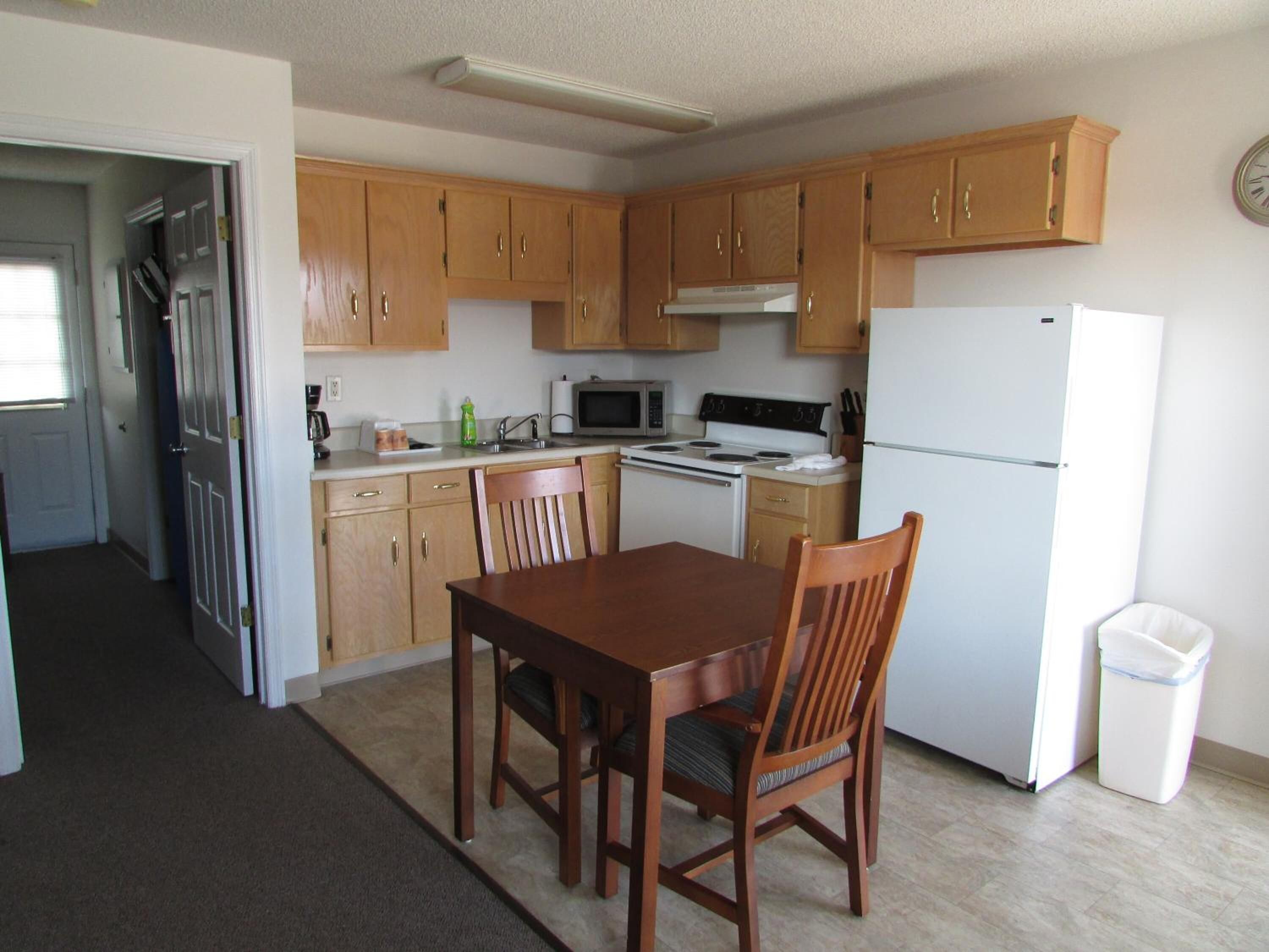 A compact kitchen with wooden cabinets, a microwave, stove, and a refrigerator.