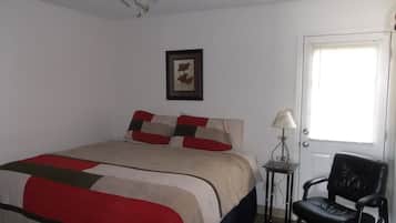 Un dormitorio con cama, ventilador de techo, un cuadro en la pared, una puerta y una silla.