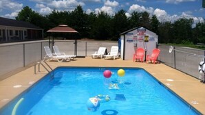 A swimming pool with lounge chairs, a lifeguard tower, and a small building with warning signs. - Douglas Inn & Suites (Blue Ridge)
