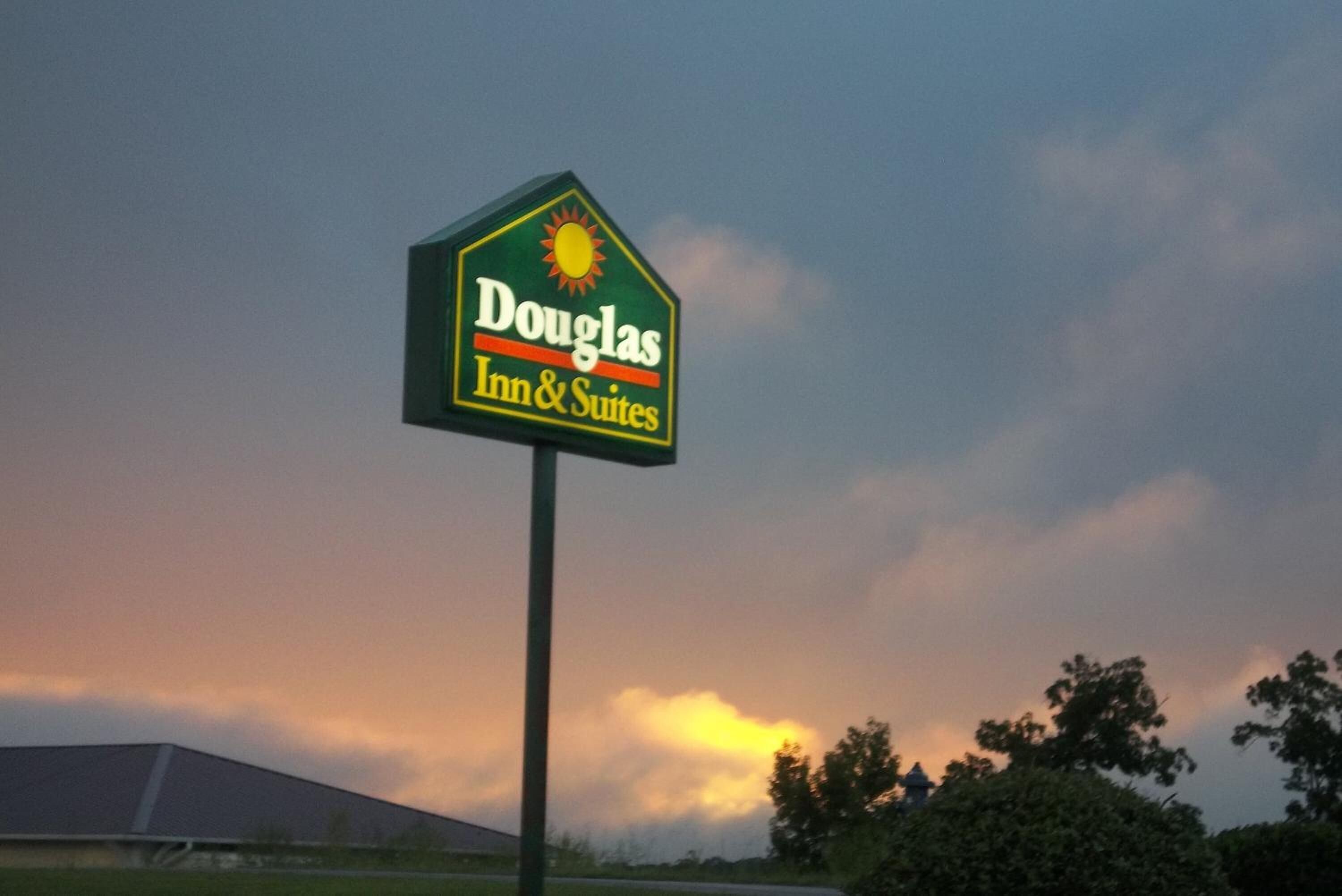 Letrero del Douglas Inn & Suites contra un cielo al atardecer.