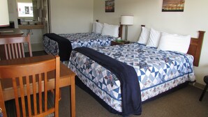 A hotel room with two beds, a desk, a chair, a lamp, and a painting on the wall. - Douglas Inn & Suites (Blue Ridge)