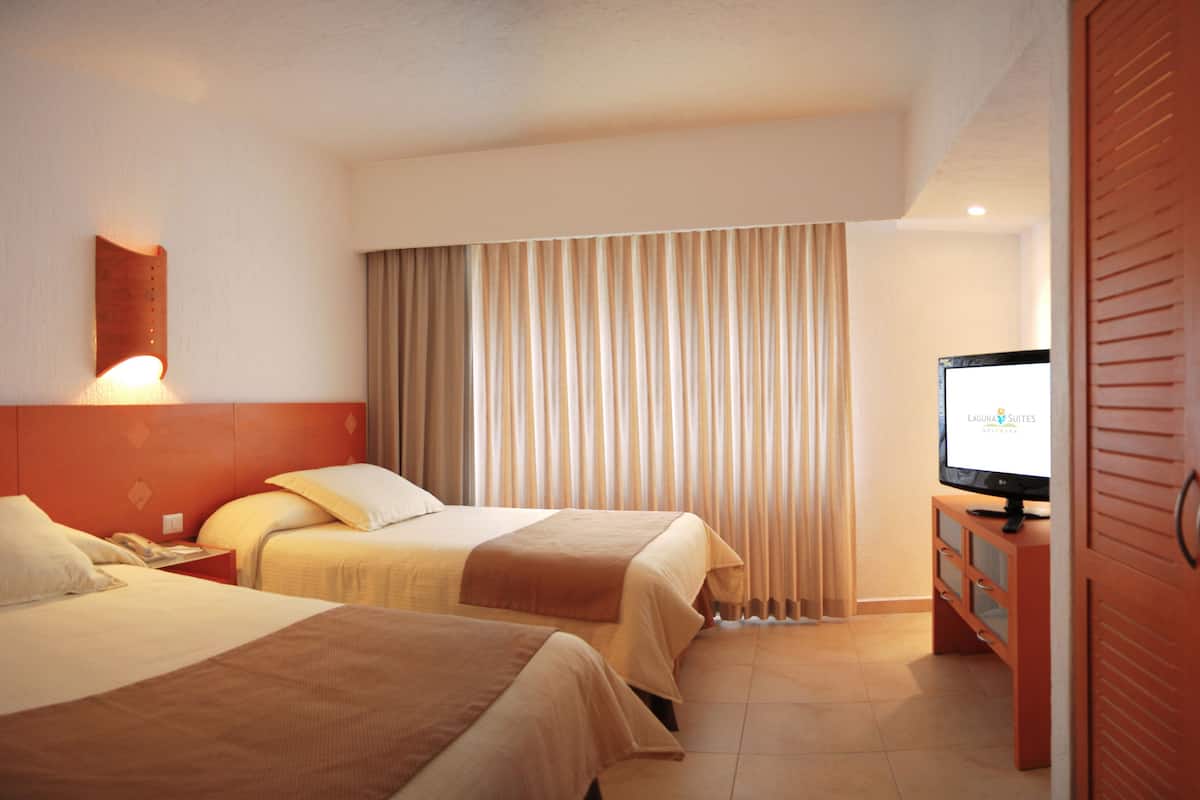 A hotel room with two beds, a TV on a wooden cabinet, and a curtain.
