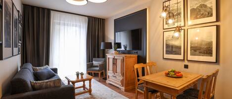 Una sala de estar moderna con sofá, una mesa de comedor con sillas, televisor y cuadros en la pared.