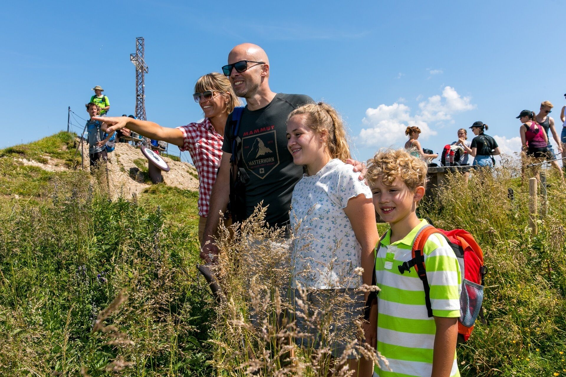 A group of people hiking on a grassy hill with a clear sky.
