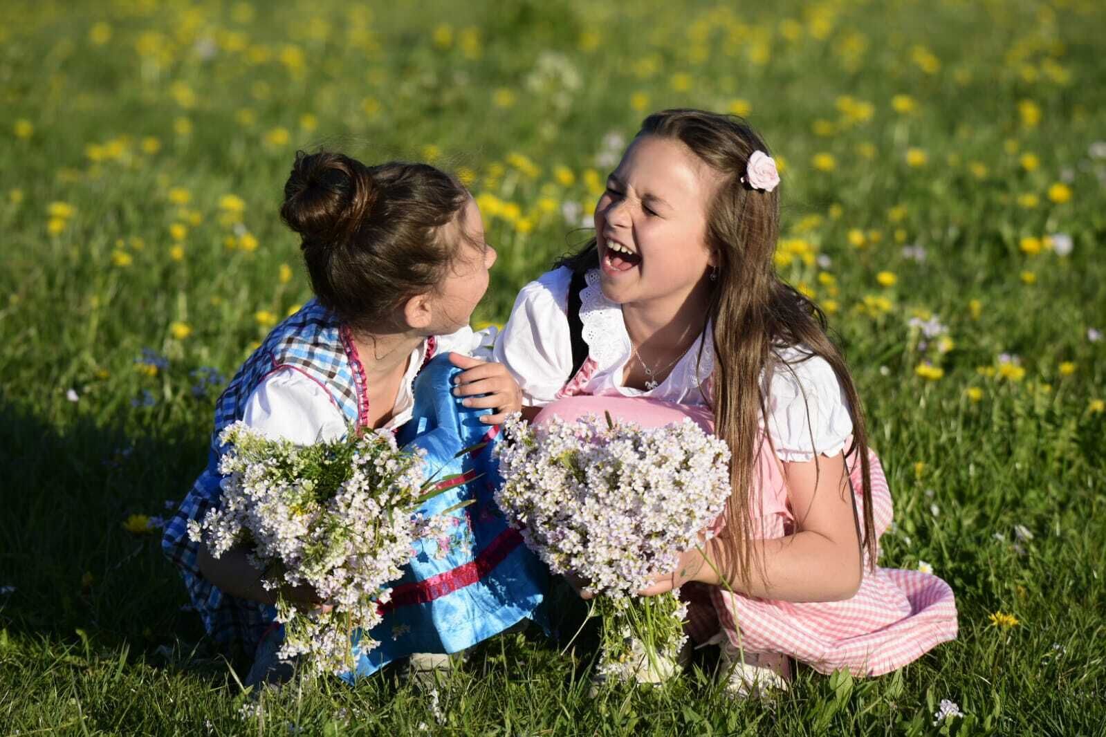 Zwei Kinder sitzen auf einer Wiese voller Blumen.