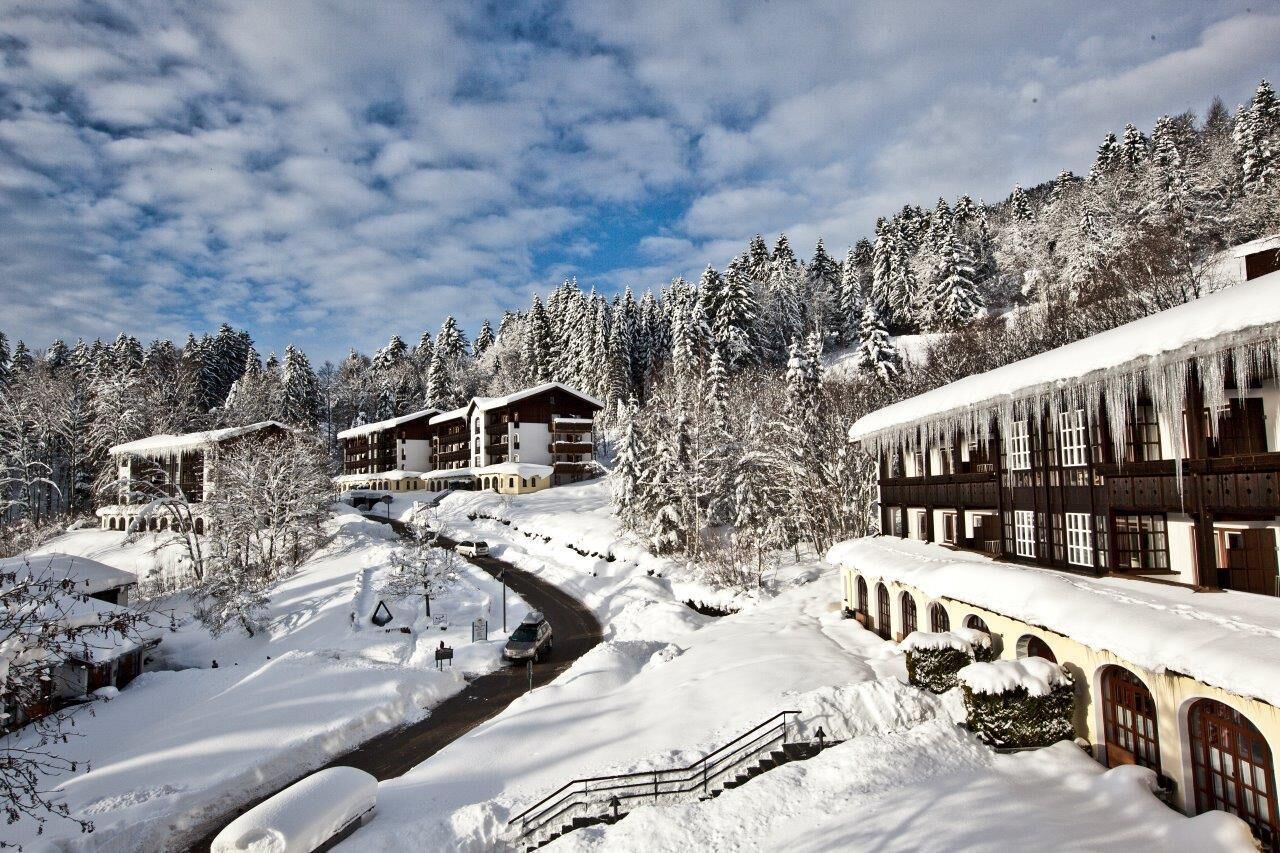 A snow-covered resort with multiple buildings, a winding road, and snow-laden trees.