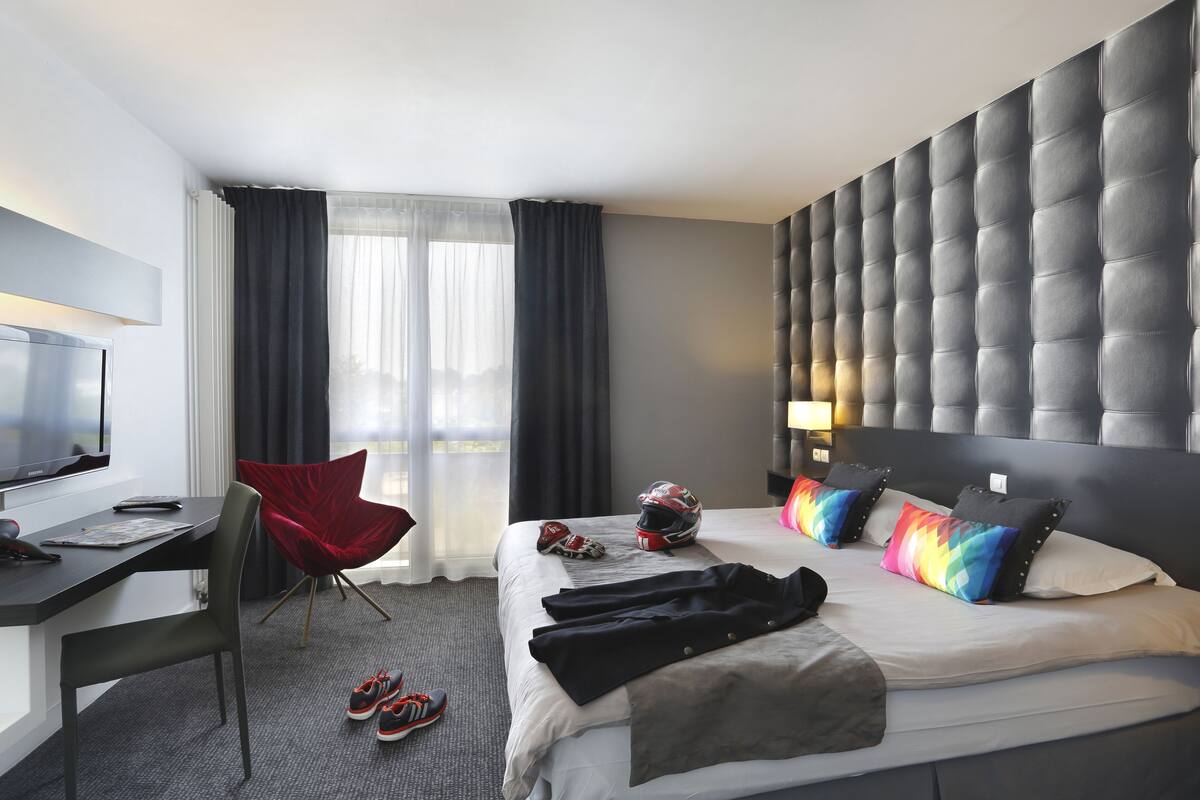 Une chambre d’hôtel moderne équipée d’un lit, d’un bureau, d’une chaise et d’un téléviseur.