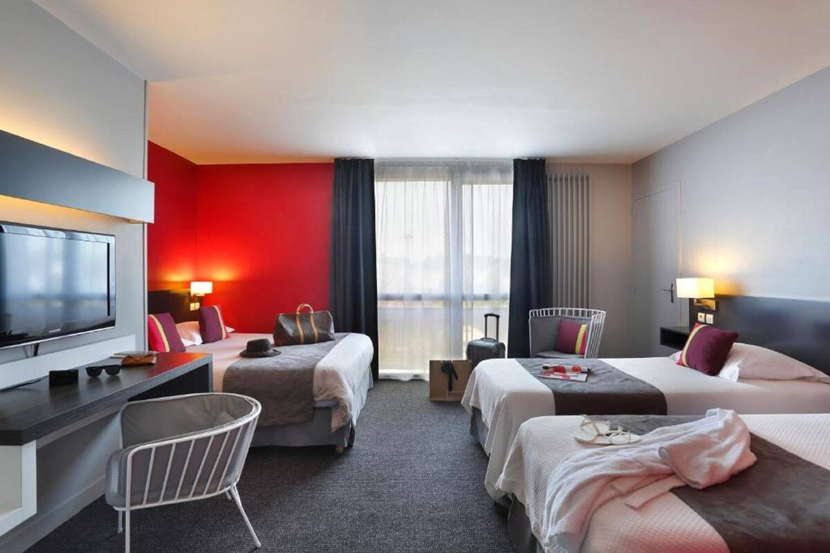 Une chambre d’hôtel avec deux lits, un bureau, une télévision et une vue sur la ville.