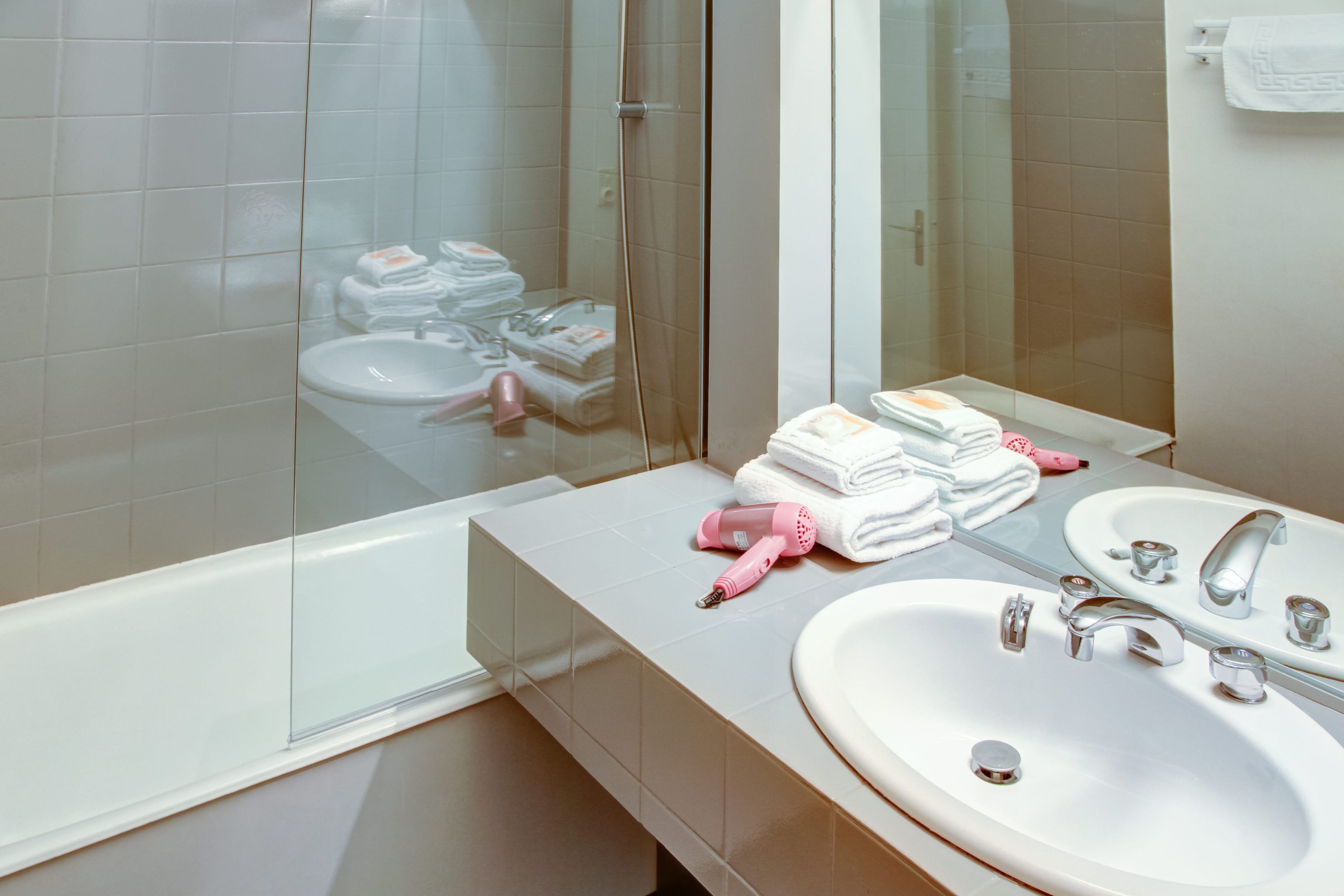A bathroom with two sinks, a glass shower enclosure, and a stack of neatly folded towels.