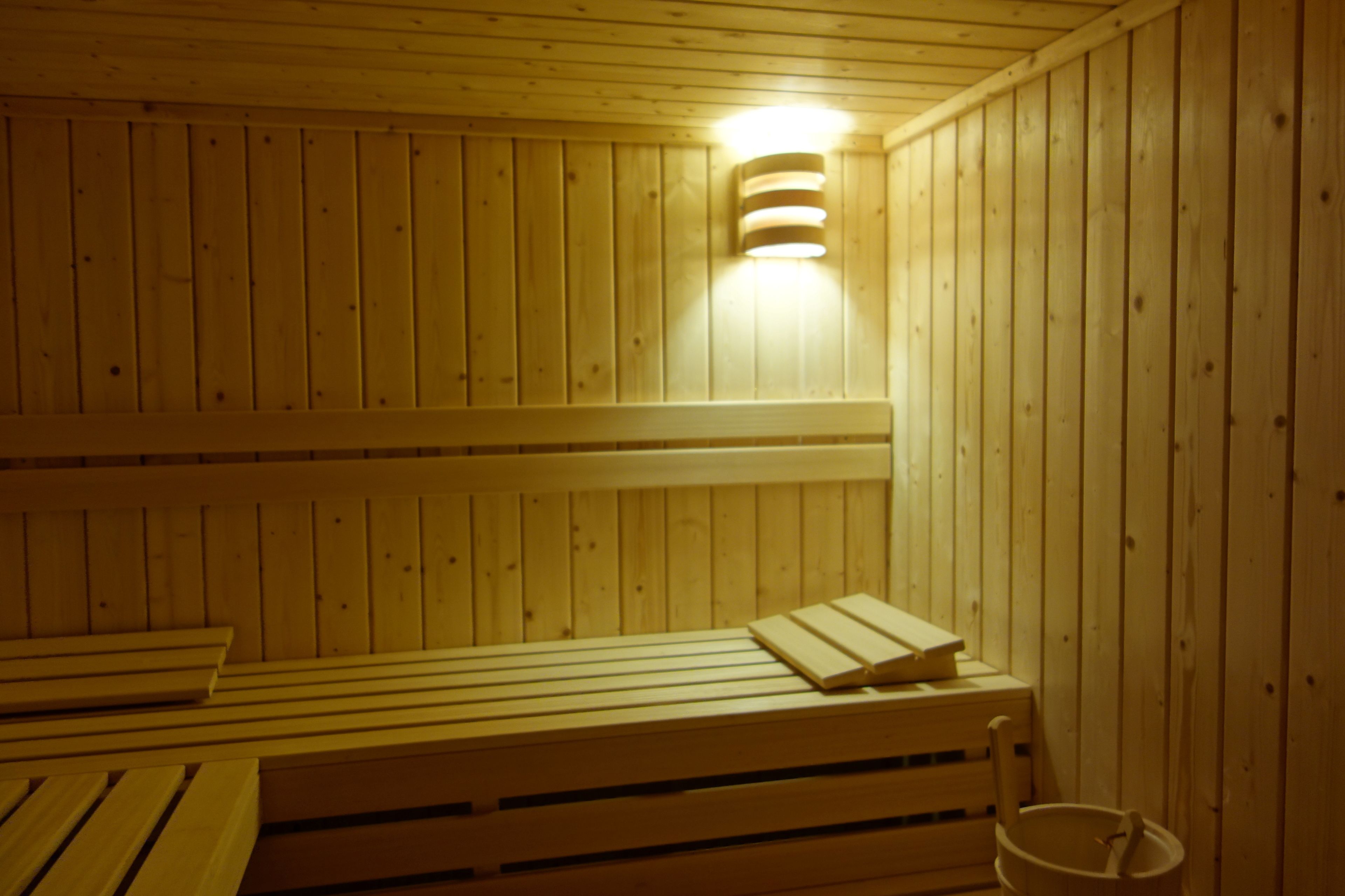Una sauna de madera con bancos y un cubo.