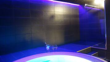 Une salle de bain moderne dotée d’un plancher chauffant, d’une douche à parois de verre et d’une baignoire avec un siège intégré.