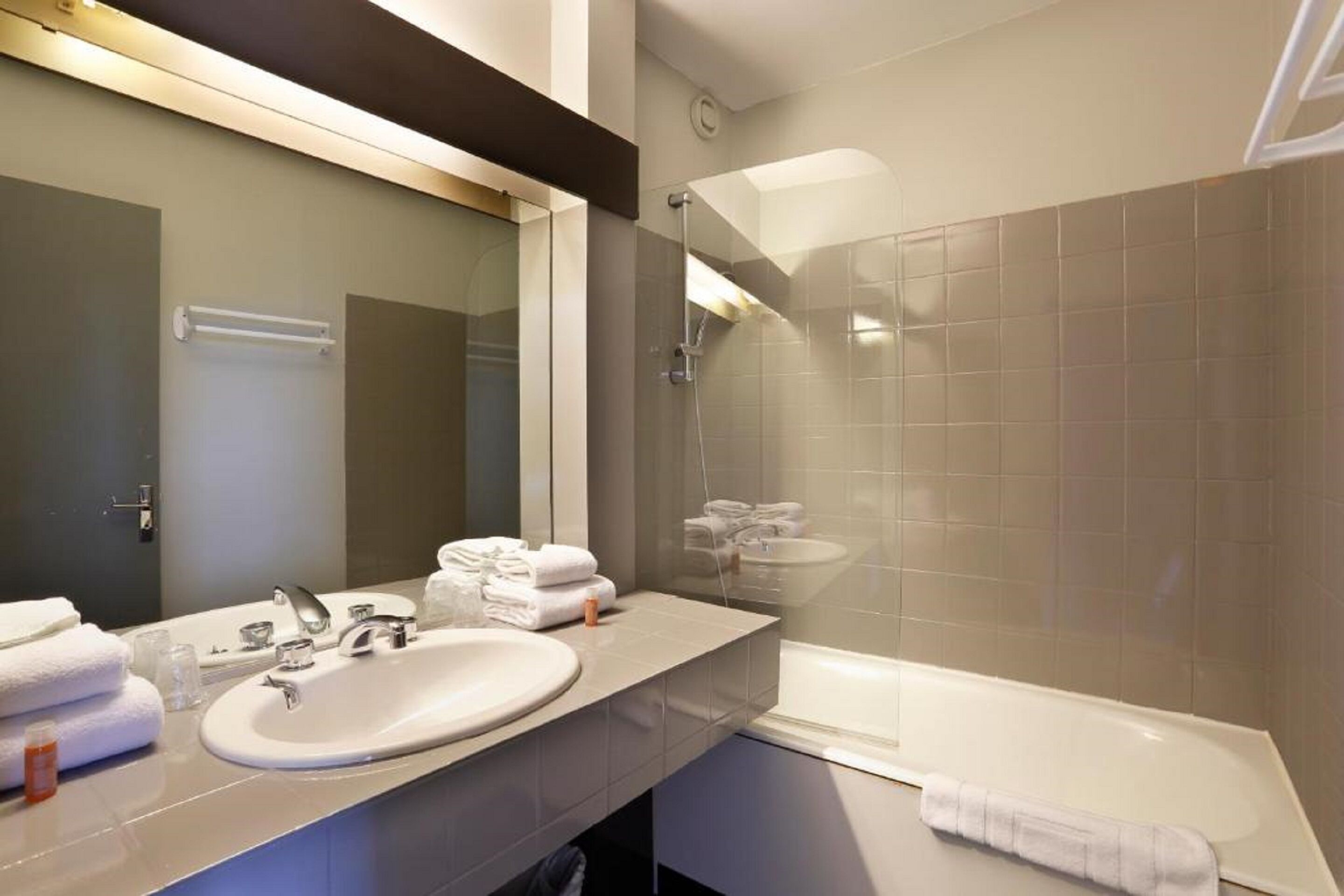 A modern bathroom with a large mirror, a sink, and a bathtub.