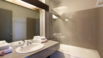 A modern bathroom with a large mirror, a sink, and a bathtub.