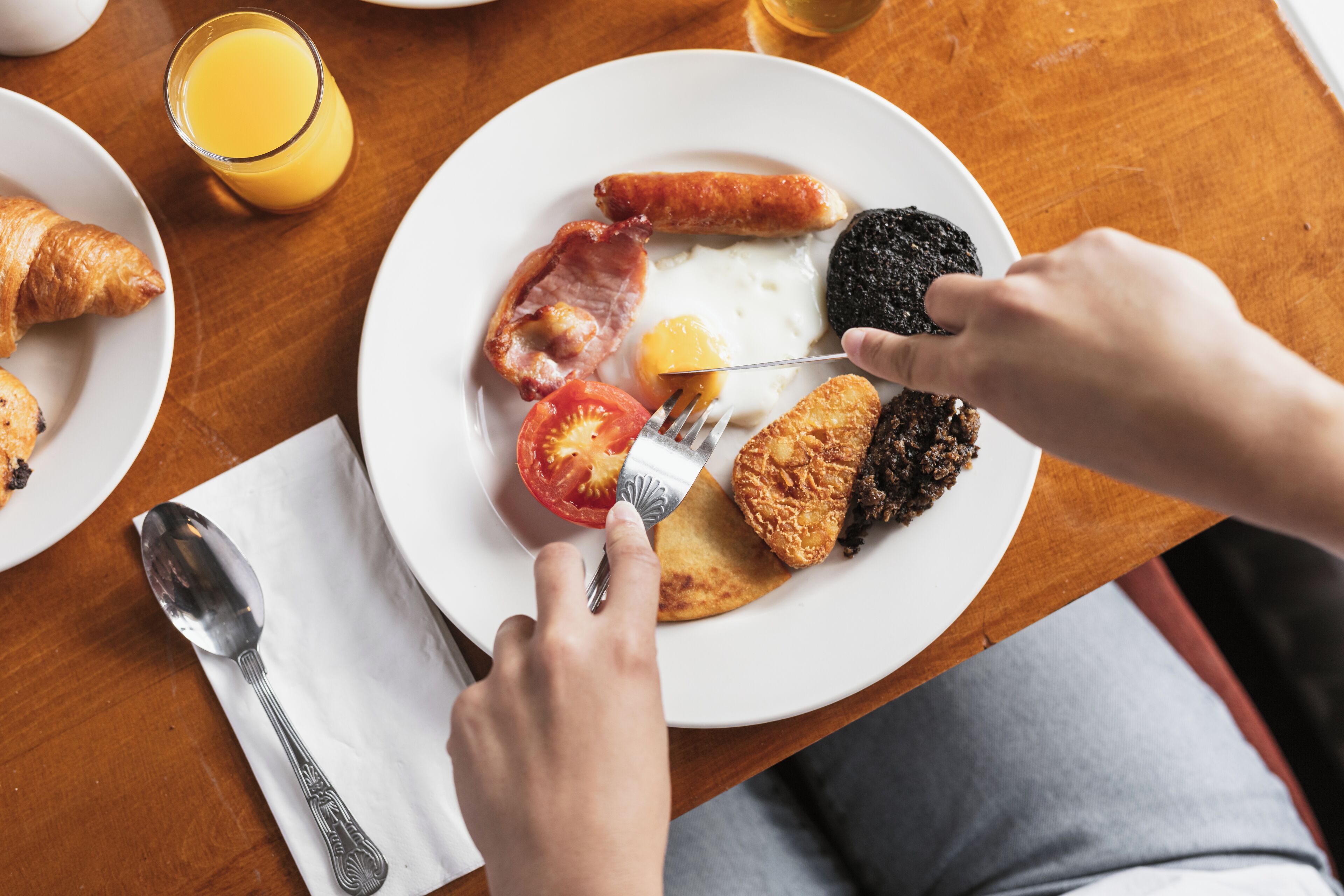 Ein Frühstücksteller mit Croissants, Würstchen, Speck, Eiern und Toast.