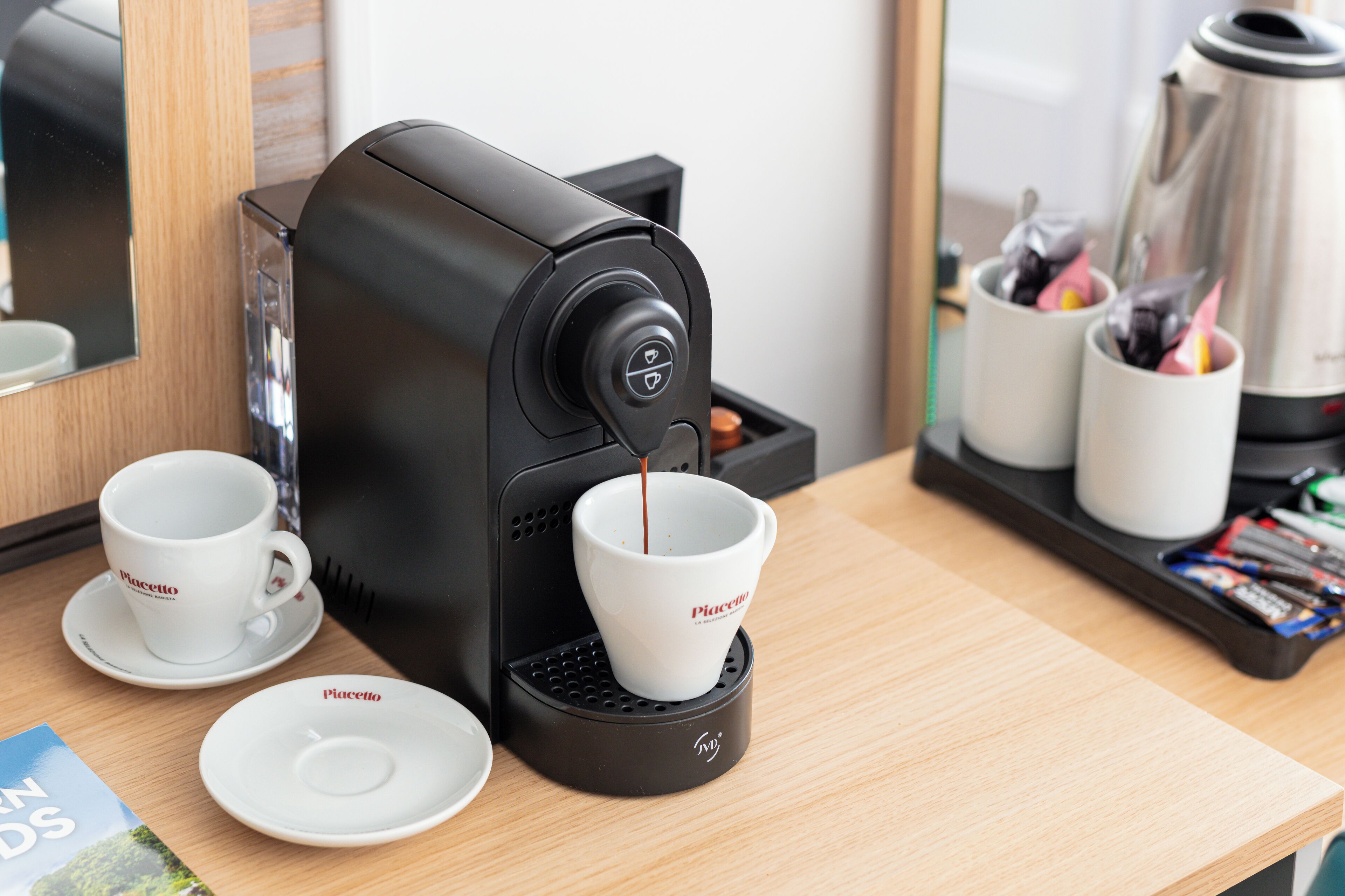 Una máquina de café sirviendo café en dos tazas sobre una mesa de madera.