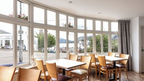 A restaurant with large windows, wooden tables, and chairs. - Caledonian Hotel (Ullapool)