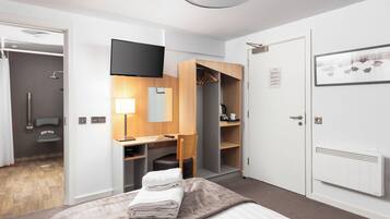 A modern hotel room with a bed, a desk, a wardrobe, and a shower area.