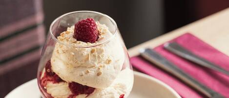 A dessert in a glass bowl on a plate, with a cookie beside it.