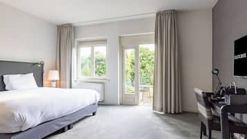 A hotel room with a bed, a desk, a chair, a TV, and a balcony with curtains.