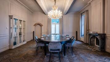 Een formele eetzaal met een ronde tafel, stoelen, een kroonluchter en een open haard.