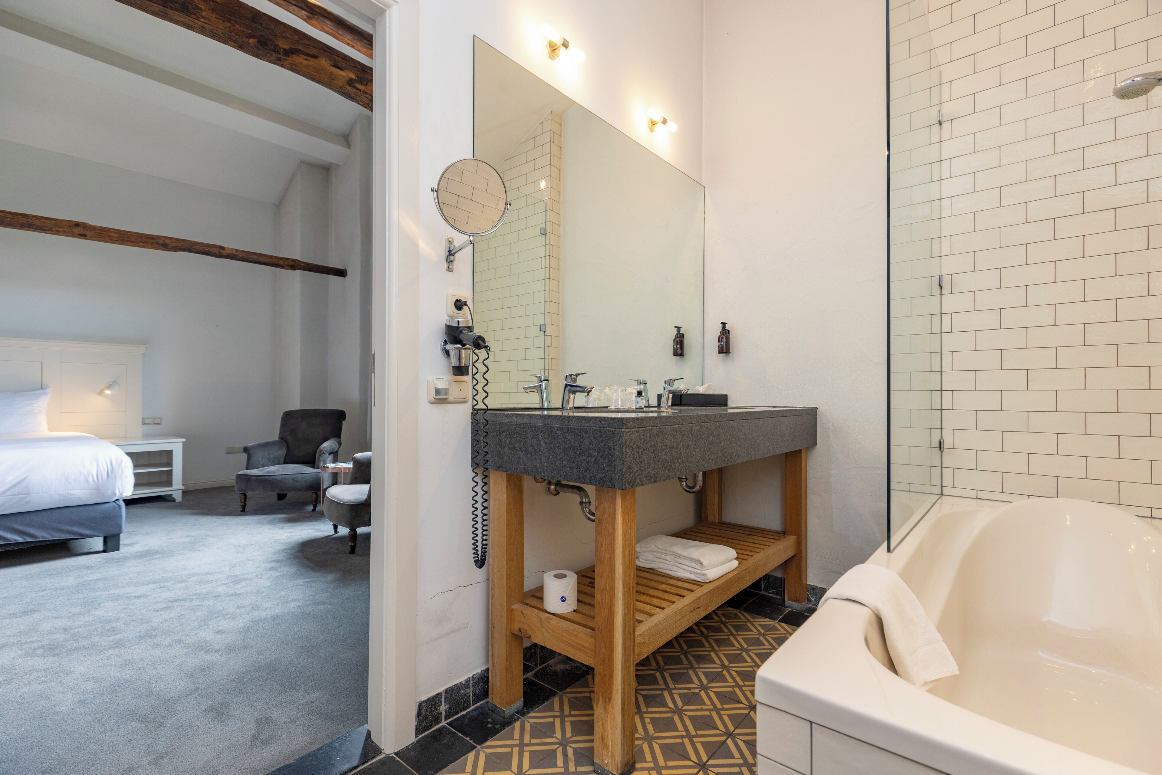 A modern bathroom with a bathtub, a wooden vanity, and a large mirror.