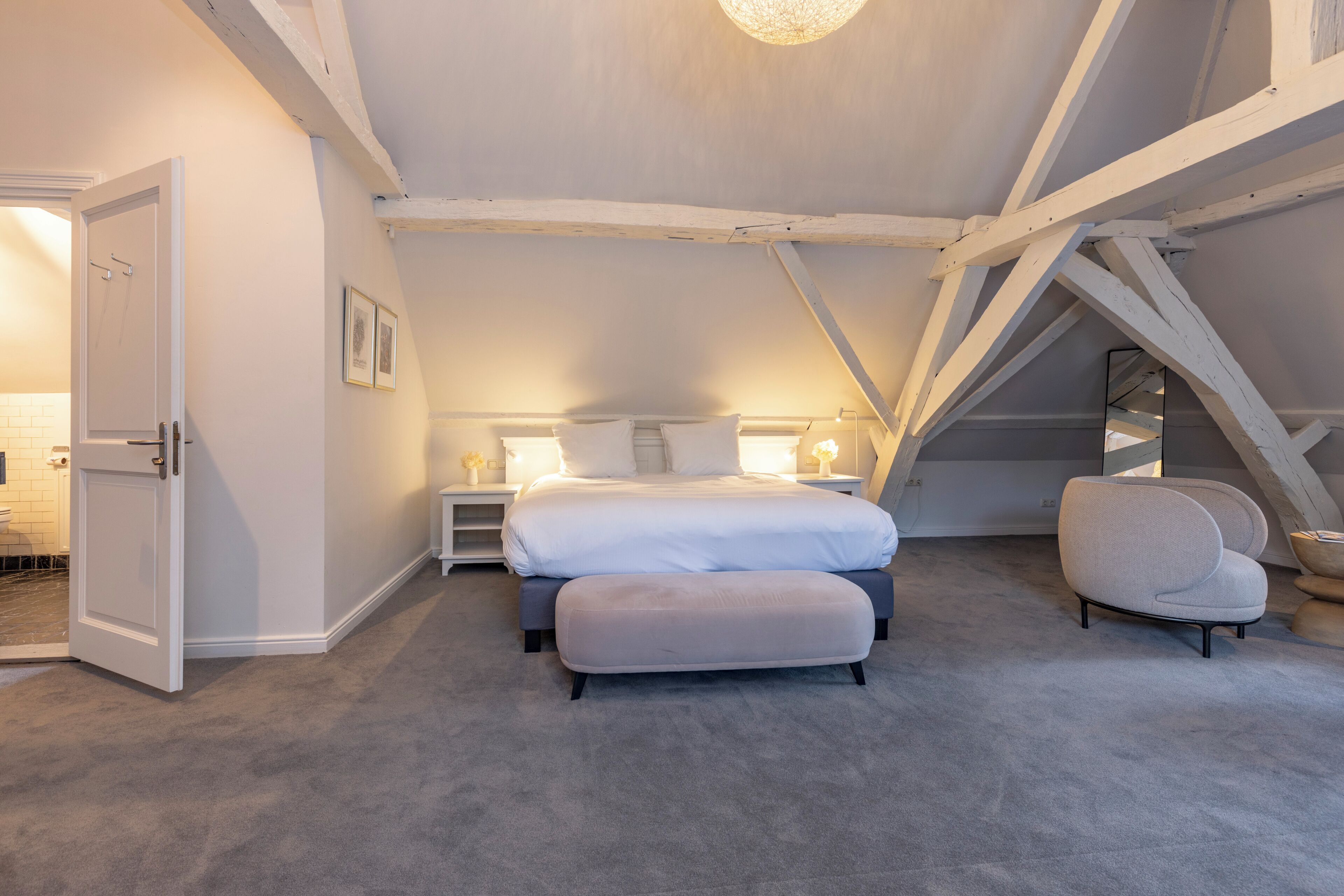 A bedroom with a bed, bedside tables, a chair, and a door.