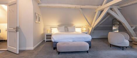 A bedroom with a bed, bedside tables, a chair, and a door.