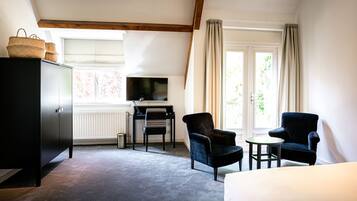 Een hotelkamer met een bed, een bureau met stoel, een televisie en een kledingkast.