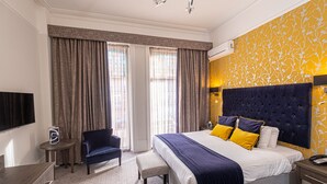 A hotel room with a large bed, a desk, a chair, and a TV. - The Durley Dean Hotel (Bournemouth)