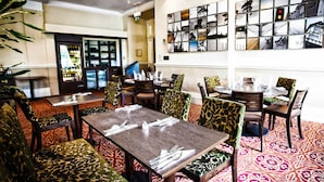 A dining area with patterned carpet, wooden tables, and chairs with green and brown upholstery. - The Durley Dean Hotel (Bournemouth)