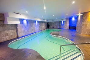 An indoor swimming pool with a tiled floor and walls, surrounded by a tiled deck area. - The Durley Dean Hotel (Bournemouth)