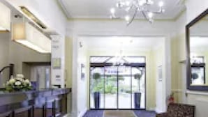 A hotel lobby with a reception desk, a chandelier, a patterned carpet, and a seating area. - The Durley Dean Hotel (Bournemouth)
