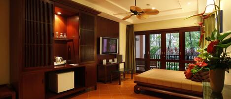 A room with a bed, a television, a desk, and a ceiling fan.