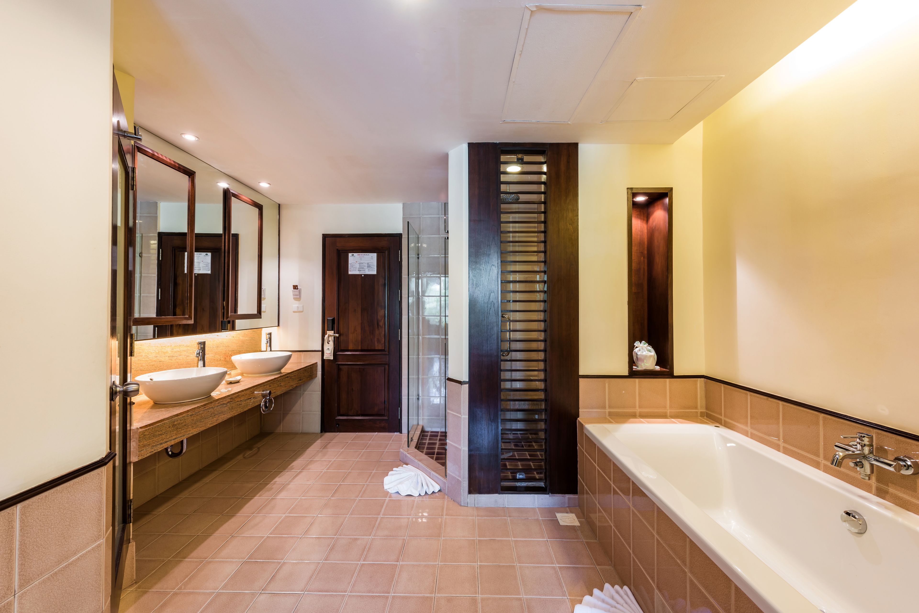 Un baño moderno con dos lavamanos, una bañera grande y un espejo.