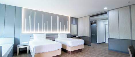Une chambre d’hôtel moderne équipée de deux lits, d’un bureau et d’un grand luminaire fixé au mur.