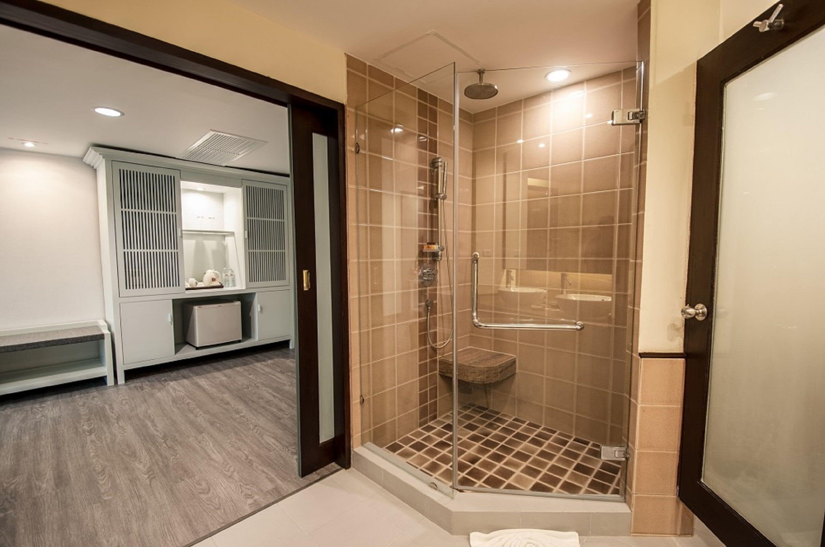 A modern bathroom with a glass-enclosed shower, a vanity with a sink, and a bench.