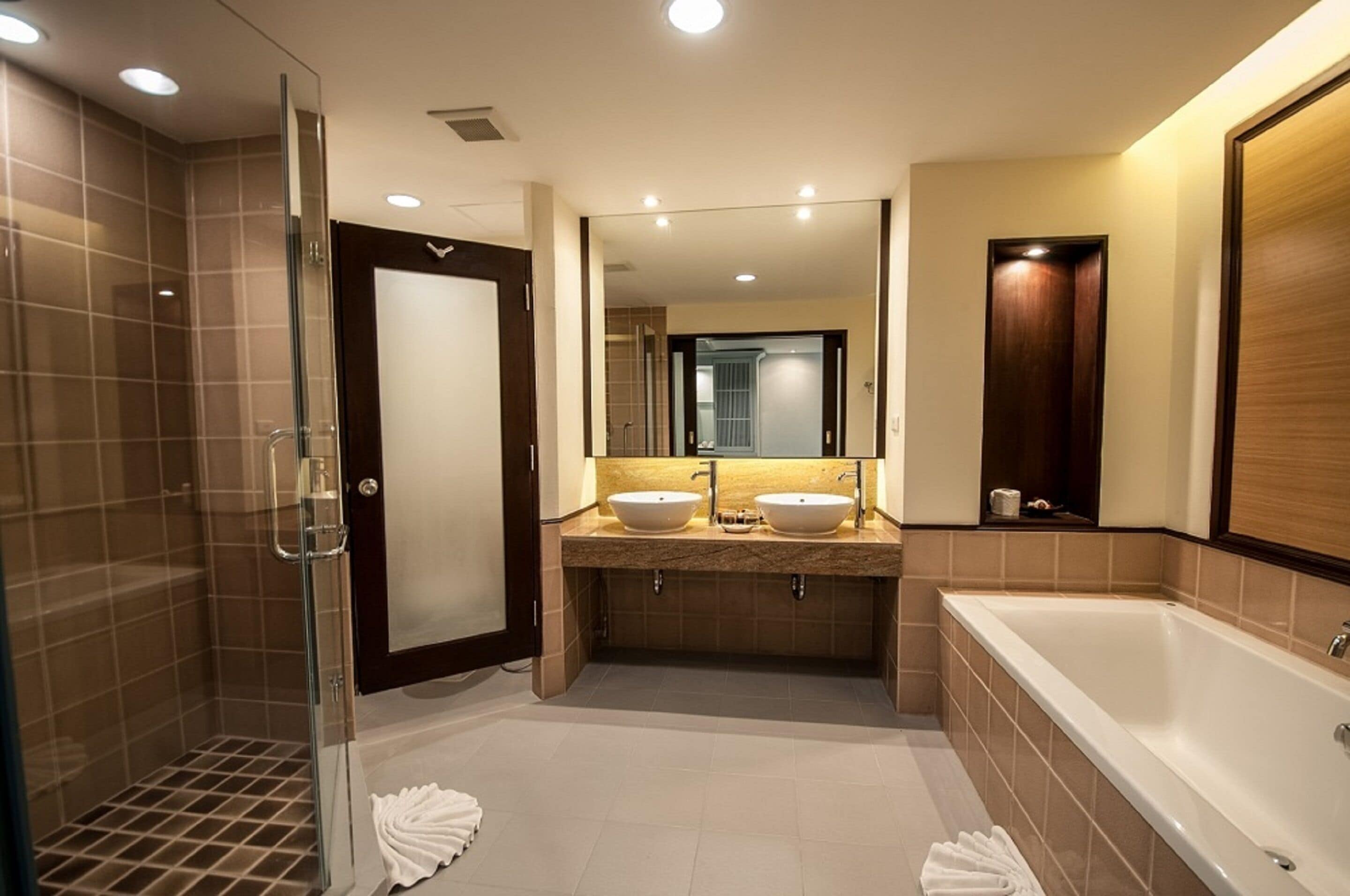 A modern bathroom with a glass shower enclosure, two sinks, a large bathtub, and a mirror above the sinks.