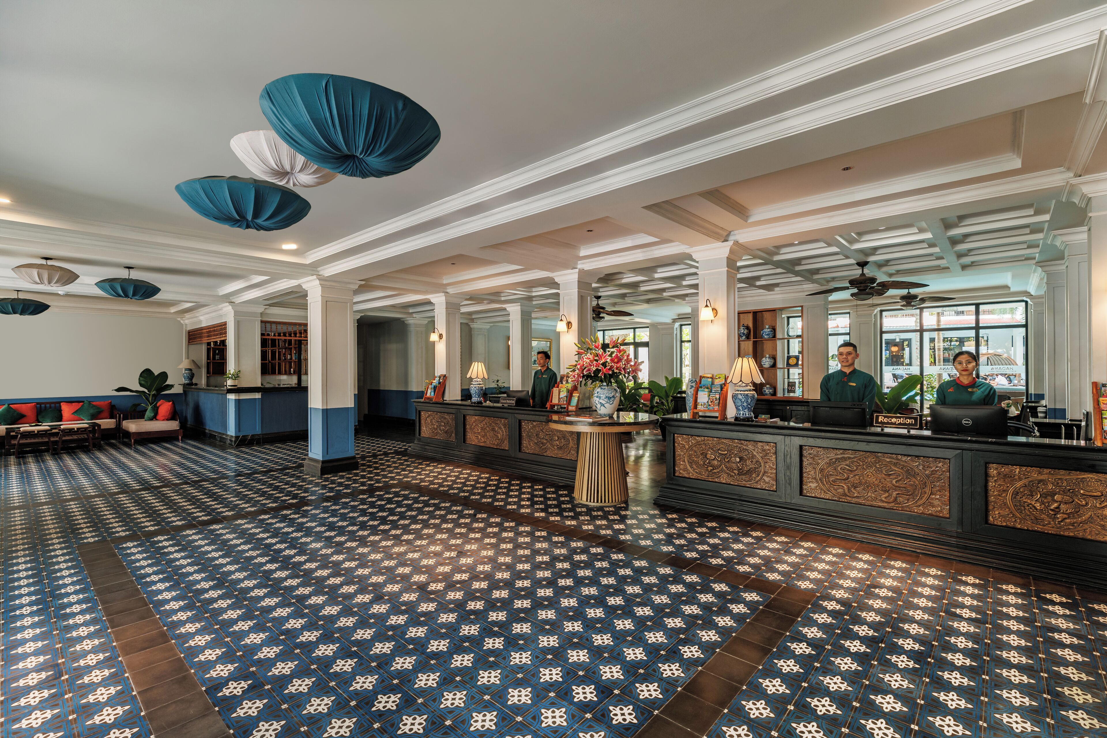 A spacious lobby with a patterned floor, a reception desk, and a seating area.