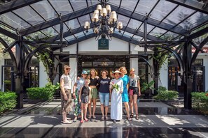 A group of people standing in front of a building with a glass roof and a chandelier. - Hadana Boutique Resort Hoi An (Da Nang)