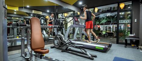 Une salle de sport équipée de tapis de course, d’appareils de musculation et d’un miroir.