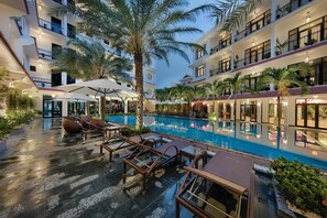 Una piscina al aire libre, sombrillas, sillones reclinables de piscina